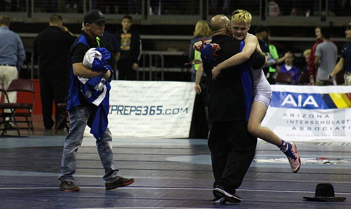 Camp Verde sophomore Korben Uhler (52-0) hugs assistant wrestling coach Mario Chagolla after he won his second straight state championship.  (VVN/James Kelley)