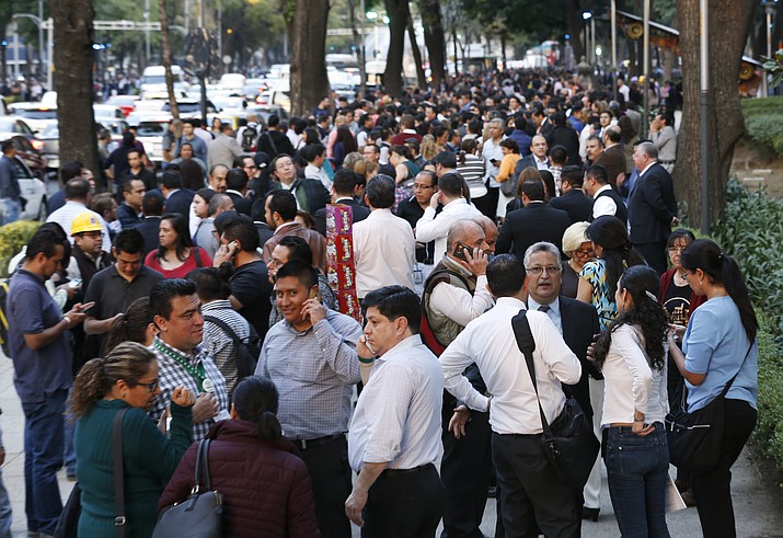 People stand along Reforma Avenue after a 7.2-magnitude earthquake shook Mexico City, Friday, Feb. 16, 2018. A powerful earthquake has shaken south and central Mexico, causing people to flee buildings and office towers in the country's capital, and setting off quake alert systems. (AP Photo/Marco Ugarte)

