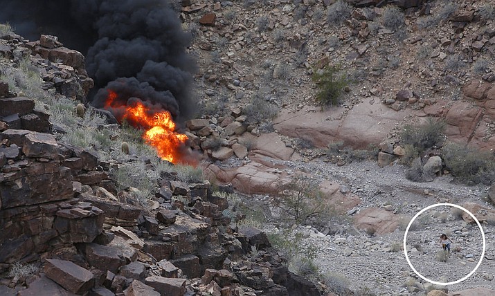 In this Saturday, Feb. 10, 2018, file photo, a survivor, lower right, walks away from the scene of a deadly tour helicopter crash along the jagged rocks of the Grand Canyon, in Arizona. Authorities say four people who survived when a sightseeing helicopter crashed at the Grand Canyon earlier this month are still hospitalized in critical condition. Three British tourists were killed on Feb. 10, while the pilot and three other Britons were injured and taken to a Las Vegas trauma center. (Teddy Fujimoto via AP, File)

