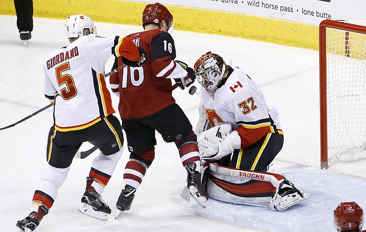 Calgary Flames goalie Jon Gillies (32) makes a save on a shot by Arizona Coyotes left wing Max Domi (16) as Flames defenseman Mark Giordano (5) gives Domi a shove during the third period of an NHL hockey game Thursday, Feb. 22, 2018, in Glendale, Ariz. The Flames defeated the Coyotes 5-2.