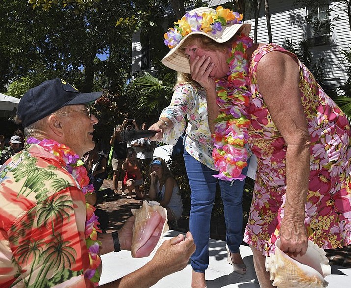 In this photo provided by the Florida Keys News Bureau, Mary Lou Smith, right, reacts to a surprise marriage proposal from Rick Race after she competed in the Conch Shell Blowing Contest Saturday, March 3, 2018, in Key West, Fla. Both Smith and Race are from Panama City Beach, Fla. Judges evaluated contest entrants from children to seniors on the quality, novelty, duration and loudness of the sounds they produced. (Rob O’Neal/Florida Keys News Bureau via AP)

