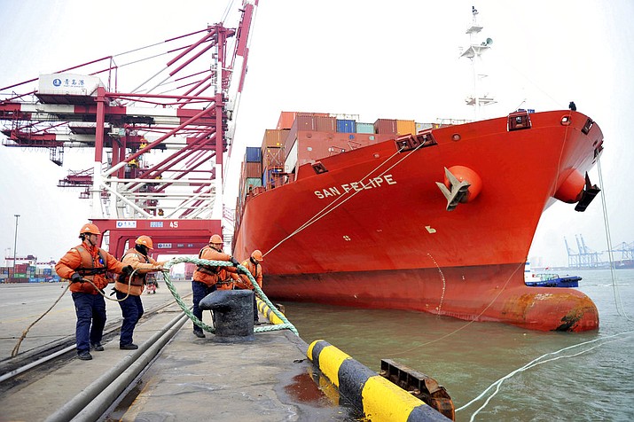 Workers tie down ropes from a container ship at a port in Qingdao in eastern China's Shandong province, Thursday, March 8, 2018. China's exports in February surged 44.5 percent over a year earlier while its politically sensitive trade surplus widened amid mounting tension with Washington. (Chinatopix via AP)