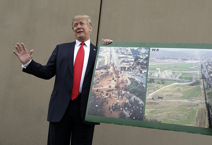 President Donald Trump holds a photo of the border area as he reviews border wall prototypes, Tuesday, March 13, 2018, in San Diego. (AP Photo/Evan Vucci)

