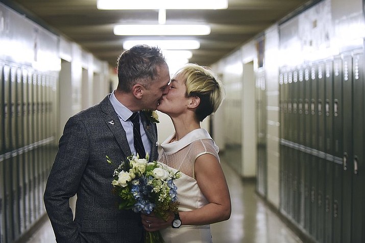 In this Saturday, March 10, 2018 photo, newlyweds Jenn Sudol and Chris Gash kiss as they are married in front of their old high school lockers at Clifton High School, in Clifton, N.J. The couple met in 1989 when they were freshman at the school. (Anne-Marie Caruso /The Record via AP)

