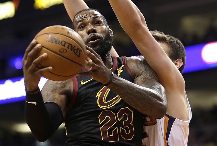 Cleveland Cavaliers forward LeBron James (23) gets fouled by Phoenix Suns forward Dragan Bender in the first half Tuesday, March 13, 2018, in Phoenix. (Rick Scuteri/AP)