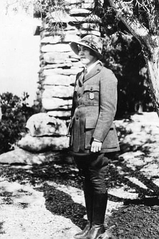 PAULINE / POLLY PATRAW, FIRST WOMAN RANGER NATURALIST AT GRCA. STANDING IN HER UNIFORM BY YAVAPAI OBSERVATION STATION. CIRCA 1930. NPS.