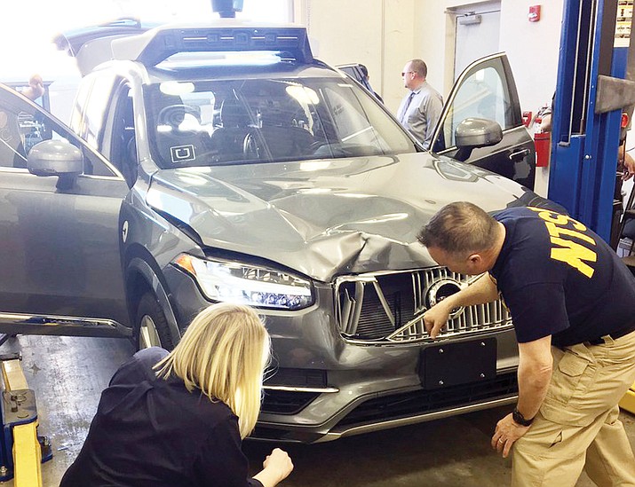In this March 20, 2018, photo provided by the National Transportation Safety Board, investigators examine a driverless Uber SUV that fatally struck a woman in Tempe, Ariz. The fatality prompted Uber to suspend all road-testing of such autos in the Phoenix area, Pittsburgh, San Francisco and Toronto. (National Transportation Safety Board via AP)