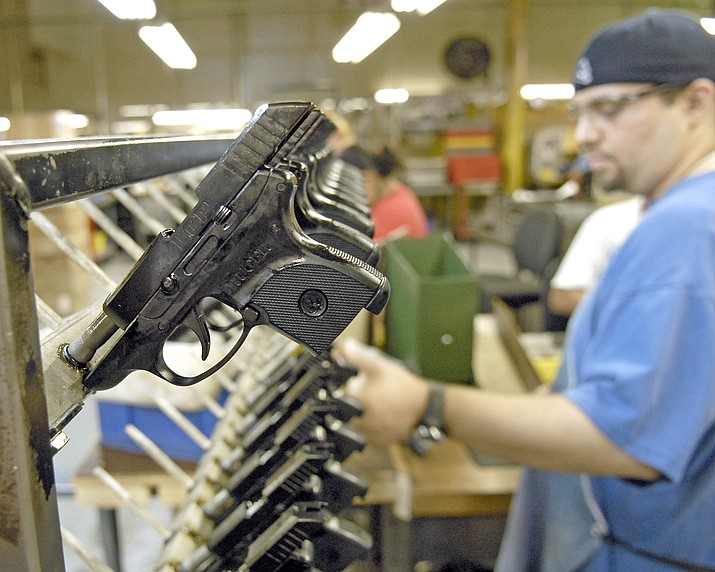 Dirkson Davis, lead assembler completes each pistol and places the Light Compact Pistol on a rack for the next phase of production. (Courier file photo)