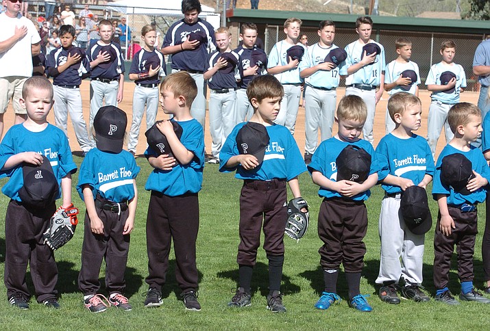 Players honor the flag as the National Anthem is sung during opening ceremonies for the 2018 Prescott Little League on Saturday, April 7, 2018, at Bill Vallely Field in Prescott. (Les Stukenberg/Courier)