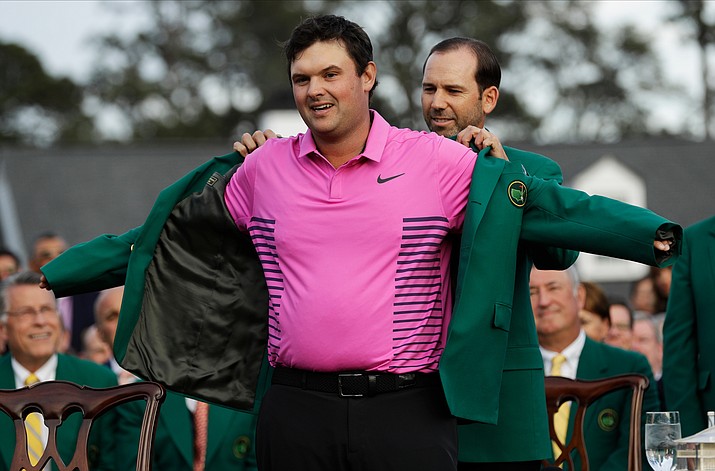 Former Masters champion Sergio Garcia, right, of Spain, helps Patrick Reed with his green jacket after winning the Masters golf tournament Sunday, April 8, 2018, in Augusta, Ga. (David J. Phillip/AP)