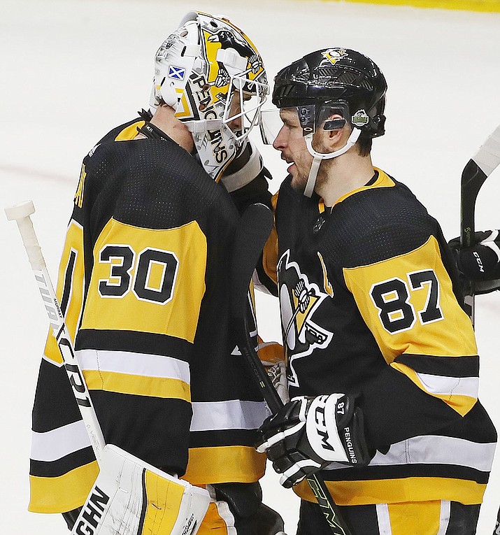 Pittsburgh Penguins' Sidney Crosby (87) congratulates goal tender Matt Murray (30) after a 7-0 shutout of the Philadelphia Flyers in Game 1 of an NHL first-round hockey playoff series in Pittsburgh, Wednesday, April 11, 2018. Crosby had his third career playoff hat trick in the game. (AP Photo/Gene J. Puskar)

