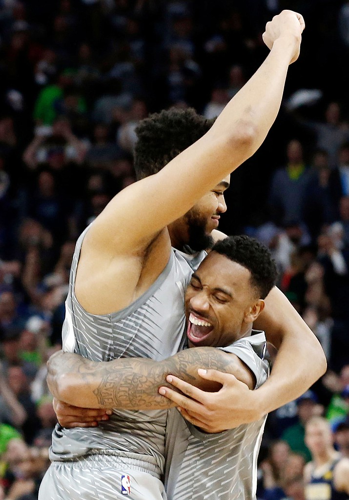 Minnesota Timberwolves' Karl-Anthony Towns, left, and Jeff Teague celebrate the team's 112-106 win in overtime against the Denver Nuggets in an NBA basketball game Wednesday, April 11, 2018, in Minneapolis. The Timberwolves made the playoffs with the win. (AP Photo/Jim Mone)
