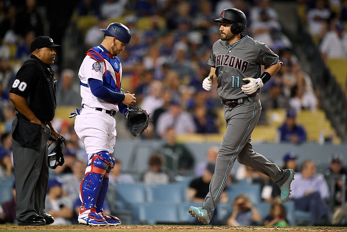 Arizona Diamondbacks' A.J. Pollock, right, scores after hitting a two-run home run as Los Angeles Dodgers catcher Yasmani Grandal, center, and home plate umpire Adrian Johnson stand at the plate during the fifth inning of a baseball game Saturday, April 14, 2018, in Los Angeles. (Mark J. Terrill/AP)
