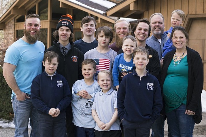 In this Friday, Feb. 16, 2018 photo, the Schwandt family poses for a portrait in front of their home in Grand Rapids, Mich. The only member not pictured is Brandon, 18. The Schwandt family has 13 sons and have welcomed a 14th into the family. The couple’s latest addition was born Wednesday evening, April 18 five days before the baby’s expected due date. (Casey Sykes /The Grand Rapids Press via AP)

