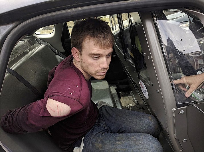 In this photo released by the Metro Nashville Police Department, Travis Reinking sits in a police car after being arrested in Nashville, Tenn., on Monday, April 23, 2018. Police said Reinking opened fire at a Waffle House early Sunday, killing at least four people. (Metro Nashville Police Department, via AP)
