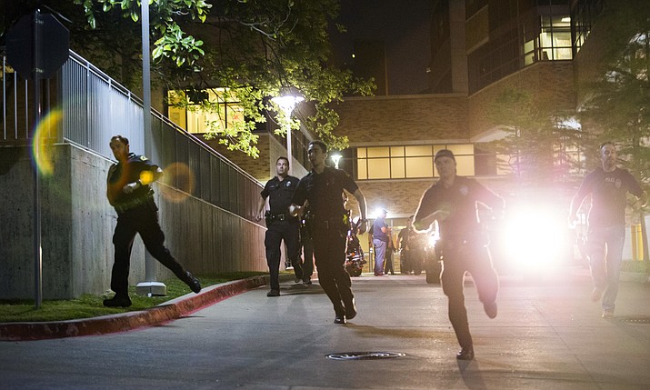 Police officers run away from the emergency room to their cars at Texas Health Presbyterian Hospital Dallas after a man shot two officers outside a Home Depot on Tuesday, April 24, 2018, in Dallas. (Ashley Landis/The Dallas Morning News via AP)

