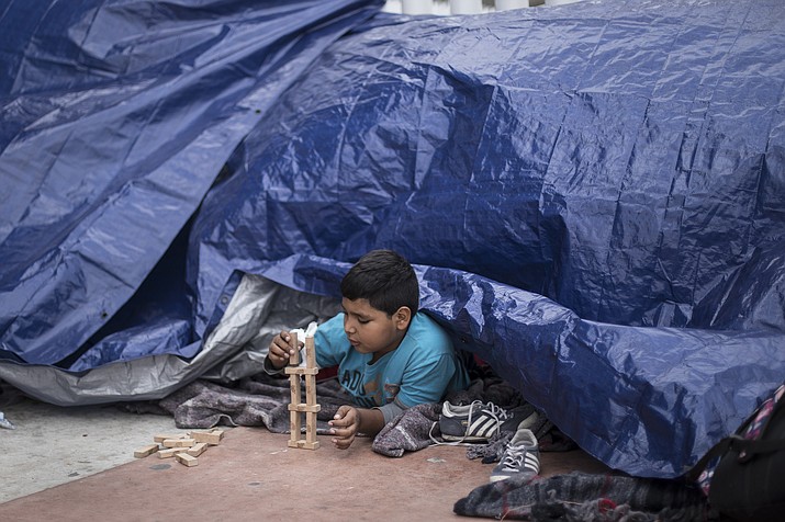 A migrant child from El Salvador plays under a tarpaulin at the El Chaparral port of Entry, in Tijuana, Mexico, Monday, April 30, 2018. bout 200 people in a caravan of Central American asylum seekers waited on the Mexican border with San Diego for a second straight day on Monday to turn themselves in to U.S. border inspectors, who said the nation's busiest crossing facility did not have enough space to accommodate them. (AP Photo/Hans-Maximo Musielik)

