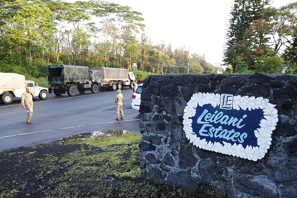 National guardsmen and police stand at the entrance to Leilani Estates, Friday, May 4, 2018, in Pahoa, Hawaii. A mandatory evacuation for the area as declared by the state. Due to unsafe conditions in the area from the recent lava eruption, residents who evacuated could not return to their homes Friday. (AP Photo/Marco Garcia)