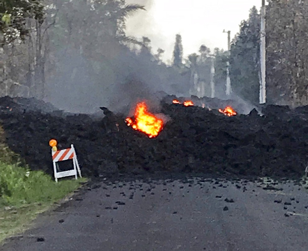 This photo provided by Hawaii Electric Light shows lava flowing over Mohala Street in the Leilani Estates area near Pahoa on the Big Island of Hawaii Friday, May 4, 2018. Nearly 1,500 people have fled from their homes after Hawaii's Kilauea volcano sent molten lava chewing through forests and bubbling up on paved streets in an eruption that one resident described as "a curtain of fire." (Hawaii Electric Light)