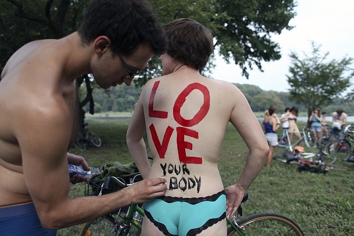 In this Sunday, Sept. 4, 2011, file photo, Cheryl Rehmann has a message painted on her back by Matthew Wellstein before the start of the naked bike ride in Philadelphia. The annual ride of naked bicyclists through Philadelphia’s streets has been so popular, organizers are teaming up with the artist behind New York City’s Bodypainting Day to launch another body-painting event. Philly Bodypainting Day will debut Sept. 8, 2018, the day of the 10th Philly Naked Bike Ride. (AP Photo/ Joseph Kaczmarek, File)

