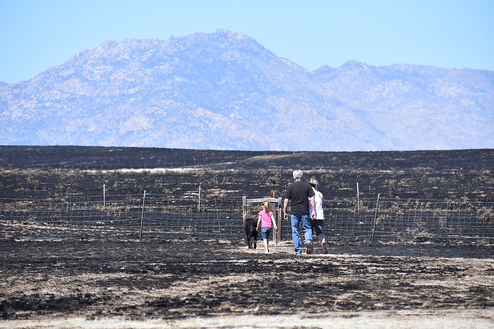 On the morning of May 12, 2018, a family walks out to the edge of the burn area of the Viewpoint Fire  near the 7000 block of Whisper Ranch Road in the Poquito Valley community of Prescott Valley, Arizona. (Richard Haddad/WNI)