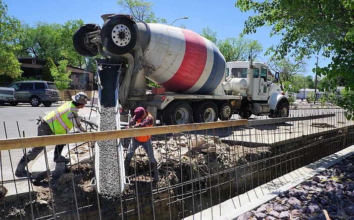 Bob Johnson, left, and Jason Johnson, with contractor B4 Enterprises, direct concrete into a trench on the drainage-improvement project underway on Prescott’s Alarcon Street. The work is redoing drainage that was reconfigured during last year’s street reconstruction. Officials say this year’s project is needed to ensure that the street has adequate flow capacity. (Cindy Barks/Courier)