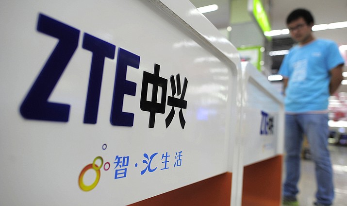 In this Oct. 8, 2012, file photo, a salesperson stands at a counter, selling mobile phones produced by ZTE Corp. at an appliance store in Wuhan in central China's Hubei province. President Donald Trump said Sunday, May 13, 2018, that he would help a Chinese telecommunications company get "back into business," saying too many jobs in China are stake since the U.S. government cut off access to its American suppliers. At issue is the U.S. Commerce Department’s move last month to block the ZTE Corp. -- a major supplier of telecoms networks and smartphones based in southern China -- from importing American components for seven years. (Chinatopix Via AP, File)