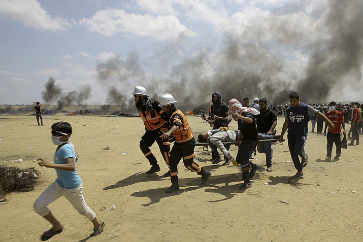 Palestinian medics and protesters evacuate a wounded youth during a protest at the Gaza Strip's border with Israel, east of Khan Younis, Gaza Strip, Monday, May 14, 2018. Thousands of Palestinians are protesting near Gaza's border with Israel, as Israel prepared for the festive inauguration of a new U.S. Embassy in contested Jerusalem. (AP Photo/Adel Hana)

