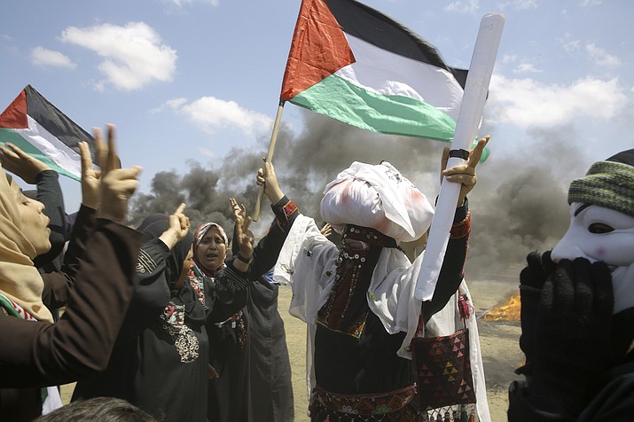 Palestinian women wave national flags and chant slogans near the Israeli border fence, east of Khan Younis, in the Gaza Strip, Monday, May 14, 2018. Thousands of Palestinians are protesting near Gaza's border with Israel, as Israel prepared for the festive inauguration of a new U.S. Embassy in contested Jerusalem. (AP Photo/Adel Hana)

