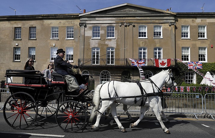 A horse drawn carriage passes decorated houses along the route that the carriage carrying Prince Harry and Meghan Markle will take after their marriage, in Windsor, England Friday, May 18, 2018. Britain's Prince Harry and Meghan Markle will marry in Windsor on Saturday May 19. (AP Photo/Kirsty Wigglesworth)

