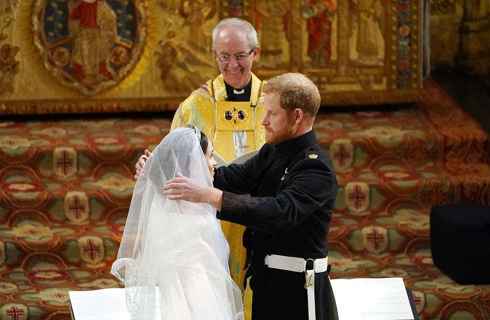 Britain's Prince Harry pulls back the veil of Meghan Markle watched by Archbishop of Canterbury Justin Welby during their wedding at St. George's Chapel in Windsor Castle in Windsor, near London, England, Saturday, May 19, 2018. (Owen Humphreys/pool photo via AP)