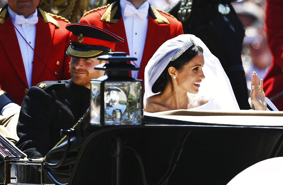Meghan Markle reacts as she rides in a carriage with her husband Britain's Prince Harry after their wedding ceremony at St. George's Chapel in Windsor Castle in Windsor, near London, England, Saturday, May 19, 2018. (Jeff J Mitchell/pool photo via AP)