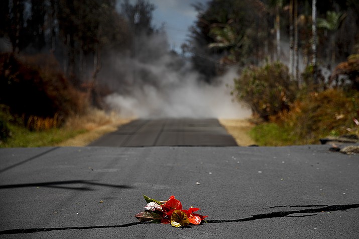 Flowers are placed on the road as an attribute to the Hawaiian volcano goddess Pele in the Leilani Estates subdivision near Pahoa, Hawaii Saturday, May 19, 2018. Two fissures that opened up in a rural Hawaii community have merged to produce faster and more fluid lava. Scientists say the characteristics of lava oozing from fissures in the ground has changed significantly as new magma mixes with decades-old stored lava.(AP Photo/Jae C. Hong)

