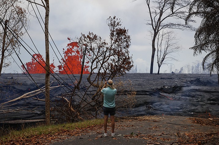 Jim Carpenter take pictures of lava erupting from fissures in the Leilani Estates subdivision near Pahoa, Hawaii, Tuesday, May 22, 2018. Authorities were racing Tuesday to close off production wells at a geothermal plant threatened by a lava flow from Kilauea volcano on Hawaii's Big Island. (AP Photo/Jae C. Hong)

