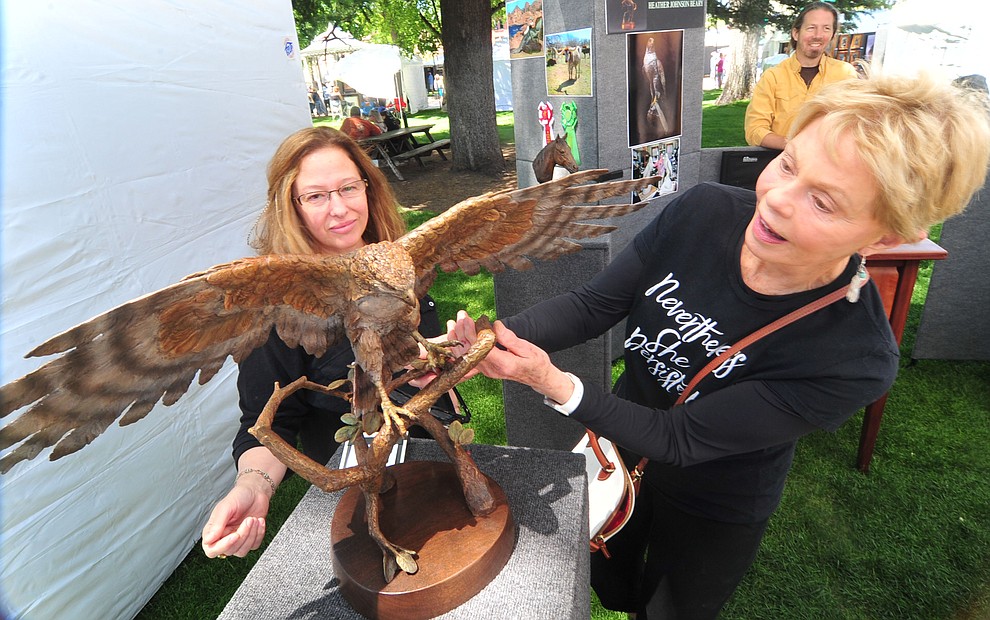 Longtime collector Toni Tenille, right, looks at Heather Johnson Beary's bronze called Red-ailed Hawk at the 44th Annual Phippen Museum Western Art Show on the courthouse plaza Saturday, May 26, 2018 in downtown Prescott. (Les Stukenberg/Courier)