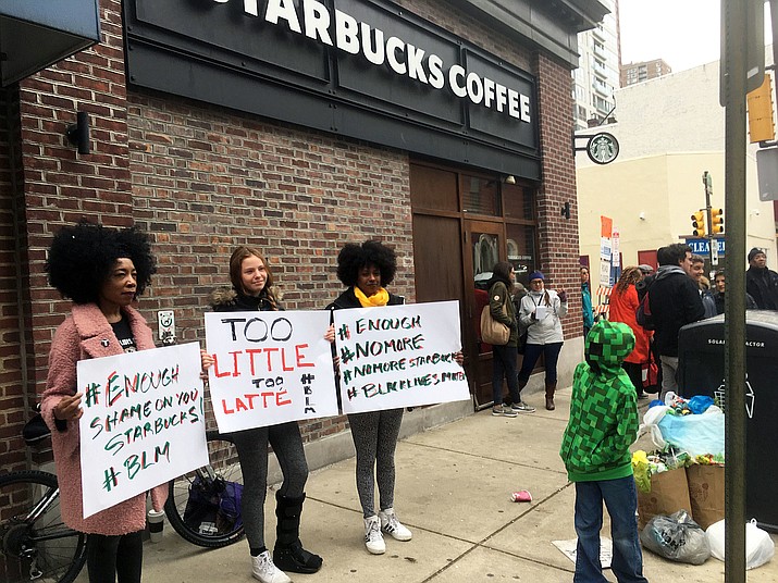 In this April 15, 2018, photo, demonstrators protest outside the Starbucks cafe in Philadelphia where two black men were arrested three days earlier for waiting inside without ordering anything. On Tuesday, May 29, 2018, the company plans to close more than 8,000 stores nationwide to conduct anti-bias training, a move intended to show how serious the company is about living up to its now-tarnished image as a neighborhood hangout where all are welcome. (AP/Ron Todt, file)