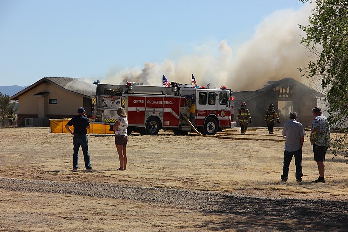 Jim Homes (second to right) and his neighbors watch as Central Arizona Fire and Medical Authority crews attempt to extinguish a fire that consumed his home in the Coyote Springs area of Prescott Valley Wednesday afternoon, May 30.