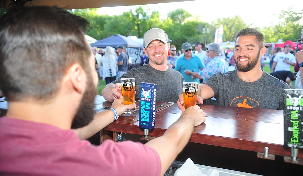 Stone Brewing's Dane Barber serves Cody Alexander and Sam Shapiro at Prescott Area Young Professionals 8th annual Party in the Pines at Prescott Mile High Middle School in Prescott Saturday, June 2, 2018. (Les Stukenberg/Courier)