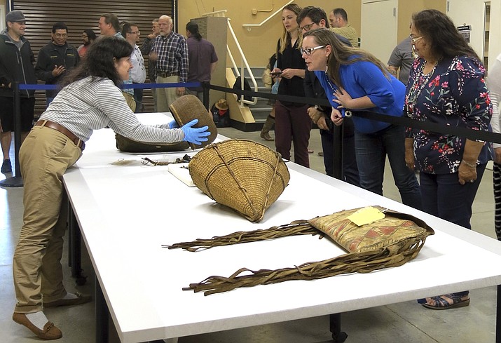 In this May 23, 2018, photo, Assistant Collections Manager for the British Museum Cynthia McGowan, left, handles a woven basket in Grand Ronde, Ore., that was collected from the Confederated Tribes of the Grand Ronde in the 1870s. Looking on are tribal chairwoman Cheryle Kennedy, right, tribal council member Kathleen George, center, and tribal attorneys Rob Greene and Jennifer Biesack. Tribal artifacts hidden away in the archives of the British Museum in London for nearly 120 years are being returned to the Oregon tribe from the British Museum and go on display Tuesday, June 5. (AP Photo/Gillian Flaccus)

