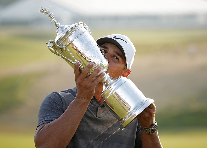 Brooks Koepka holds up and kisses the Golf Champion Trophy after winning the U.S. Open Golf Championship, Sunday, June 17, 2018, in Southampton, N.Y. (Carolyn Kaster/AP Photo)