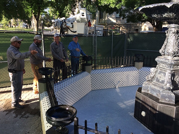 Yavapai County Facilities Department employees toss inaugural coins into about 4 inches of water June 26 as the newly restored fountain fills up. It will be officially unveiled at 2 p.m. Friday, June 29. (Sue Tone/Courier)
