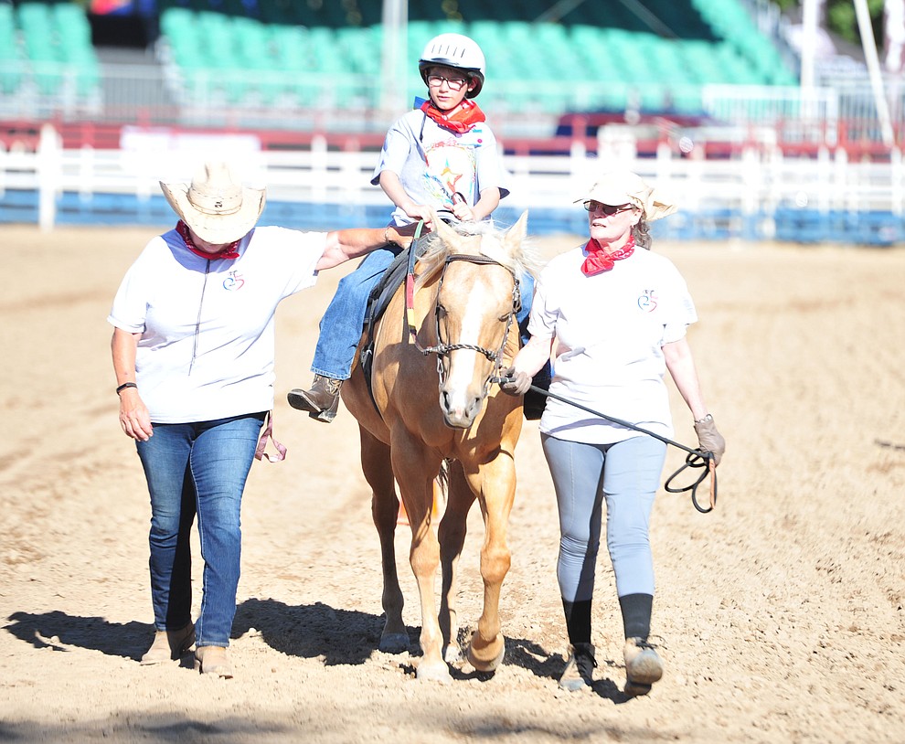 Sandy Dessero and Cindy Roche walk with Brandon Widtfeldt during the Happy Hearts Rodeo for exceptional children before the opening performance of the Prescott Frontier Days Rodeo Thursday, June 28, 2018. (Les Stukenberg/Courier)