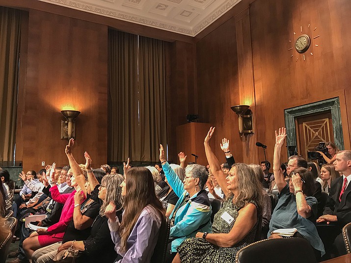 Audience members at a Senate hearing on a bill to compensate “downwinders” – people affected by radiation from nuclear testing – raise their hands when asked if they are downwinders. (Photo by Bryan Pietsch/Cronkite News)