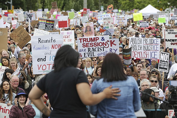 Monserrat Padilla, left, puts her arm around Aurora, an undocumented immigrant, as Aurora speaks to several thousand demonstrators gathered outside the Federal Detention Center in SeaTac to protest the separation of families crossing the U.S.-Mexico border and President Donald Trump's immigration policies as part of a rally for Families Belong Together, Saturday, June 30, 2018, in Seattle. (Genna Martin /seattlepi.com via AP)

