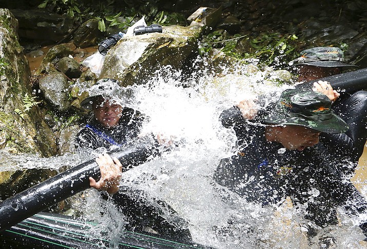 Thai soldiers try to connect water pipes that will help bypass water from entering a cave where 12 boys and their soccer coach have been trapped since June 23, in Mae Sai, Chiang Rai province, in northern Thailand Saturday, July 7, 2018. Thai authorities are racing to pump out water from the flooded cave before more rains are forecast to hit the northern region. (AP Photo/Sakchai Lalit)

