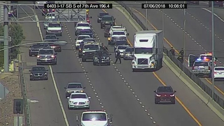 Officers confront a man with a knife on I-17 who started running across the southbound traffic lanes at Seventh Avenue and jumped onto someone's vehicle Friday, July 6, 2018. He then jumps off the vehicle and runs to the edge of the overpass and flips over a guardrail, falling below. (Arizona Department of Transportation)