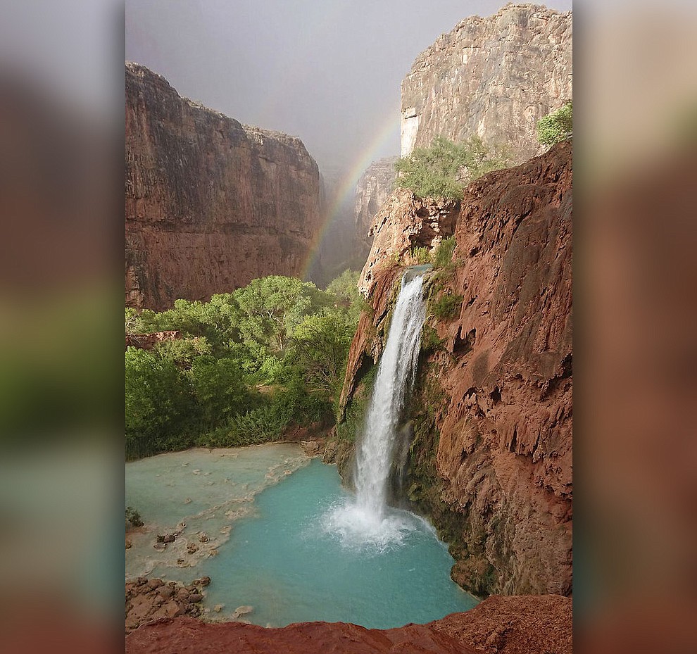 This Wednesday, July 11, 2018 photo released by Benji Xie shows a rainbow over a waterfall on the Havasupai reservation in Supai, Ariz. About 200 tourists were evacuated July 12 from a campground on tribal land near famous waterfalls deep in a gorge off the Grand Canyon. (Benji Xie via AP)