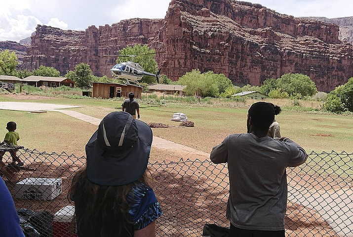 This Thursday, July 12, 2018 photo released by Benji Xie shows a helicopter landing to rescue people from flooding on the Havasupai reservation in Supai, Ariz. Rescue workers were evacuating about 200 tourists Thursday who were caught in flash flooding at a popular campground on tribal land near the Grand Canyon where visitors go to see towering blue-green waterfalls. (Benji Xie via AP)