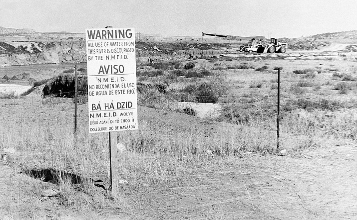 In this Nov. 13, 1979, file photo, while United Nuclear Corp. uses a combination of hand work and heavy machinery to clear up a uranium tailings spill, signs along the Rio Puerco warn residents in three languages to avoid the water in Church Rock, N.M. The Navajo Nation is urging Congress to expand a federal law that compensates people exposed to radiation. (AP Photo/SMH, File)