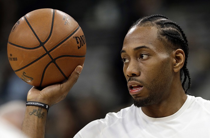 In this Jan. 5, 2018, file photo, San Antonio Spurs forward Kawhi Leonard handles a ball before an NBA basketball game against the Phoenix Suns in San Antonio. Two people familiar with the situation say San Antonio and Toronto have reached an agreement in principle on a trade that will send Kawhi Leonard to the Raptors and DeMar DeRozan to the Spurs. One of the people says the Spurs also are sending Danny Green to the Raptors as part of the deal. Both people spoke to The Associated Press on condition of anonymity Wednesday, July 18, 2018, because the deal has not been finalized. (Eric Gay/AP, File)